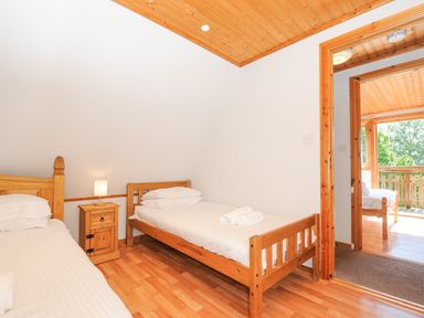 A bedroom with two single wooden beds a wooden nightstand and a lamp at Lodge 47 - Primrose Lodge Finlakes Holiday Park near Chudleigh