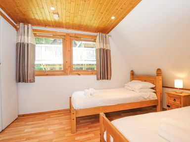 A bedroom with two single beds and a wooden ceiling at Lodge 47 - Primrose Lodge Finlakes Holiday Park near Chudleigh