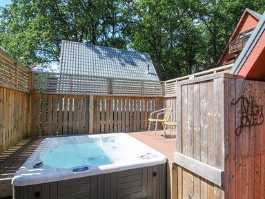 An outdoor hot tub and two chairs on a wooden deck surrounded by wooden fencing at Lodge 47 - Primrose Lodge Finlakes Holiday Park near Chudleigh