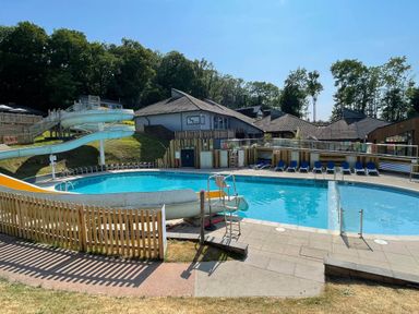 An outdoor swimming pool with a water slide and lounge chairs at Lodge 47 - Primrose Lodge Finlakes Holiday Park near Chudleigh