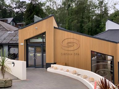 Exterior of a building with wooden cladding and a sign that reads Sirona Spa at Finlakes Holiday Park near Chudleigh