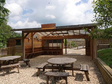 An outdoor seating area with wooden benches tables and a shelter labeled the cabana at Finlakes Holiday Park near Chudleigh