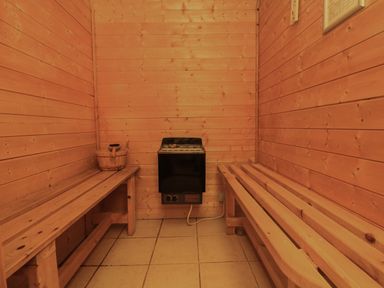 An empty wooden sauna room with benches on both sides and a heater on the back wall at Lodge 58 - Oak Tree Lodge Finlakes Holiday Park near Chudleigh