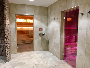 A tiled room with two sauna rooms with glass doors and a drinking fountain at Lodge 58 - Oak Tree Lodge Finlakes Holiday Park near Chudleigh