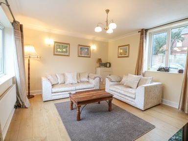 A living room with two sofas a wooden coffee table and framed pictures on the wall at Tiffany's Cottage in Gorleston-On-Sea
