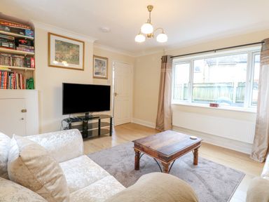 A living room with a couch a wooden coffee table a television on a stand and a bookshelf at Tiffany's Cottage in Gorleston-On-Sea