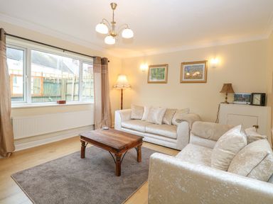 A living room with two sofas a wooden coffee table a floor lamp and framed pictures on the walls at Tiffany's Cottage in Gorleston-On-Sea