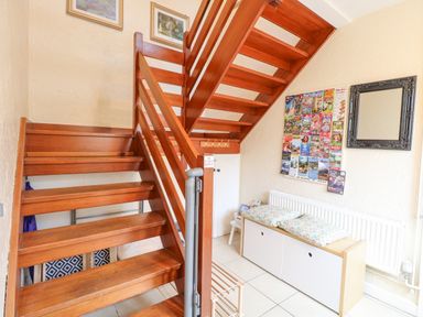 A wooden staircase next to a bench with cushions a mirror and a display of postcards on the wall at Tiffany's Cottage in Gorleston-On-Sea