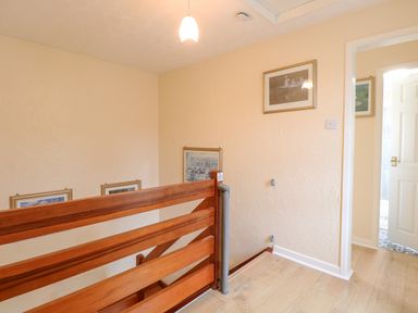 A stair landing with wooden balustrade and framed pictures on the walls at Tiffany's Cottage in Gorleston-On-Sea