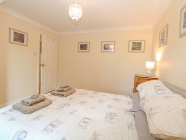 A bedroom with a double bed and folded towels on the bed at Tiffany's Cottage in Gorleston-On-Sea