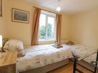 A bedroom with two single beds a window and framed pictures at Tiffany's Cottage in Gorleston-On-Sea