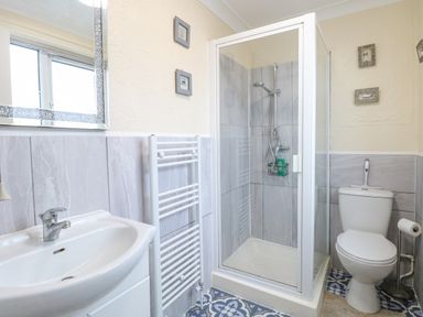 A bathroom with a sink cabinet, towel radiator, shower enclosure, and toilet at Tiffany's Cottage in Gorleston-On-Sea