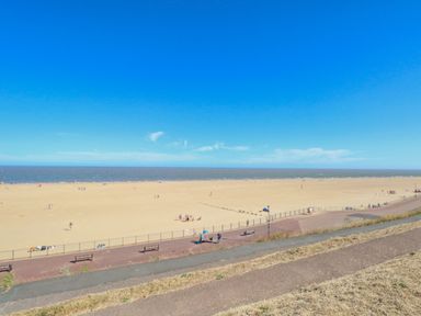 A beach with people on the sand and a promenade with benches near the sea at Tiffany's Cottage in Gorleston-On-Sea
