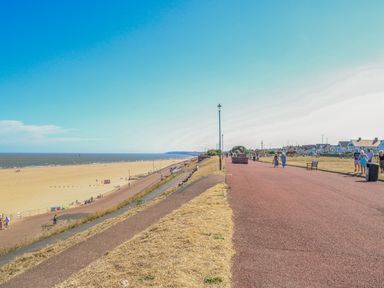 A pathway with street lamps and people walking beside a beach and houses at Tiffany's Cottage in Gorleston-On-Sea