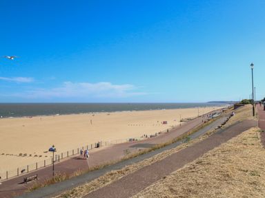 A sandy beach with a promenade and people walking at Tiffany's Cottage in Gorleston-On-Sea