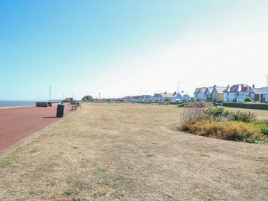 A seaside promenade with benches and houses along the coast at Tiffanys Cottage in Gorleston-On-Sea