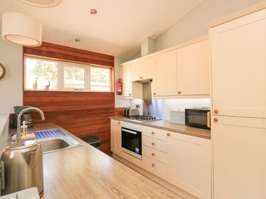 A kitchen with wooden countertops white cabinets a stainless steel sink and kettle at Woodland View 7 - Oak Cabin Finlakes Holiday Park near Chudleigh