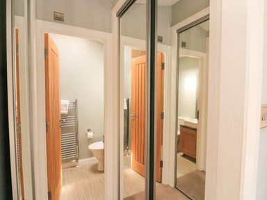 A hallway with a wooden door leading to a bathroom with a toilet and towel rack at Woodland View 7 - Oak Cabin in Finlakes Holiday Park near Chudleigh