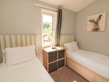 A bedroom with two single beds and a nightstand with a lamp between them at Woodland View 7 - Oak Cabin Finlakes Holiday Park near Chudleigh