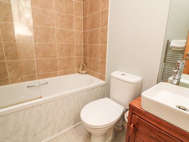 A bathroom with a bathtub toilet sink and a wooden cabinet at Woodland View 7 - Oak Cabin Finlakes Holiday Park near Chudleigh