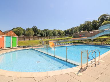 An outdoor swimming pool with a waterslide and lounge chairs at Woodland View 7 - Oak Cabin in Finlakes Holiday Park near Chudleigh