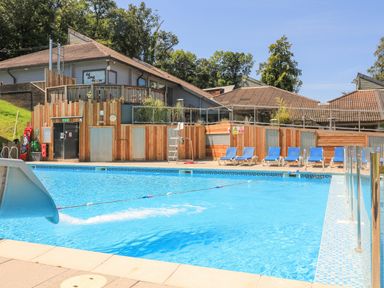 An outdoor swimming pool with a water slide and blue lounge chairs at Woodland View 7 - Oak Cabin Finlakes Holiday Park near Chudleigh