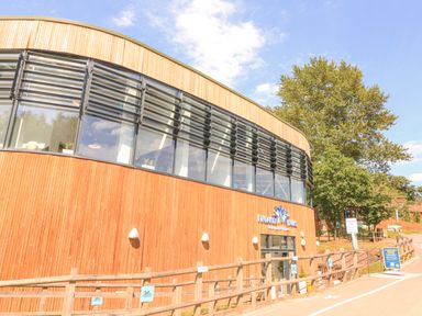 Exterior view of a wood-paneled building with large windows and signage for Finlake Falls Waterpark and Fitness at Finlakes Holiday Park near Chudleigh