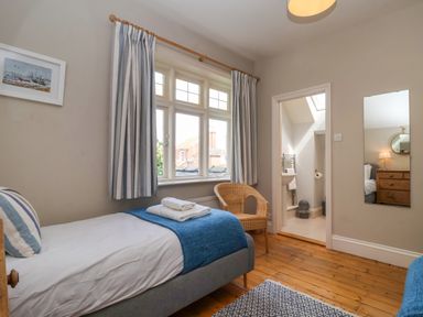 A bedroom with a single bed a chair and an ensuite bathroom at Samphire House in Southwold