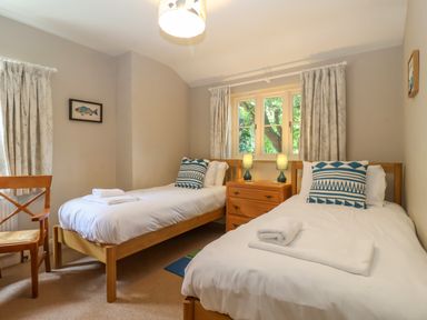 A bedroom with two single beds a wooden chair and a wooden dresser with lamps at Samphire House in Southwold