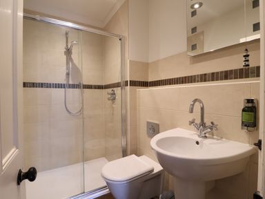 A bathroom with a shower enclosure a toilet and a sink at Samphire House in Southwold