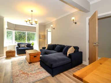 A living room with a navy blue sofa and armchair a wooden coffee table and a large window at Eller Cottage in Windermere