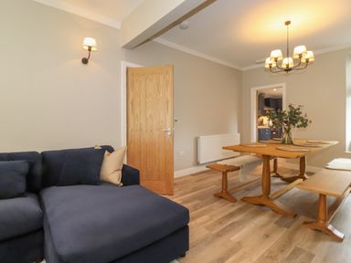 A living room with a dark blue sofa and wooden dining table with benches at Eller Cottage in Windermere