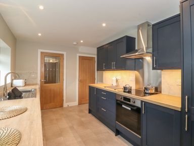 A kitchen with dark cabinets wooden countertops stainless steel oven and range hood at Eller Cottage in Windermere