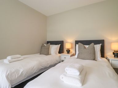 A bedroom with two single beds with white bedding pillows and towels on the beds at Eller Cottage in Windermere
