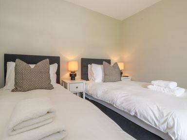 A bedroom with two single beds side by side with patterned pillows and folded towels on each bed at Eller Cottage in Windermere