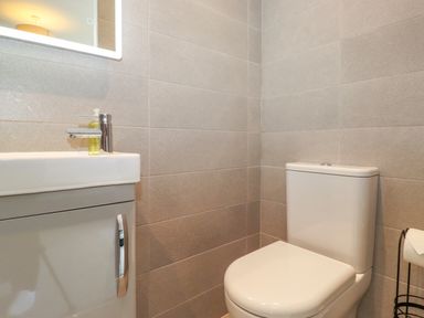 A bathroom with a toilet sink and mirror at Eller Cottage in Windermere
