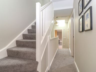 A carpeted staircase and hallway with framed pictures on the wall at Eller Cottage in Windermere