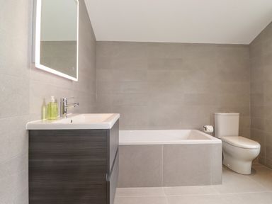 A bathroom with a bathtub toilet and sink with a mirror above at Eller Cottage in Windermere