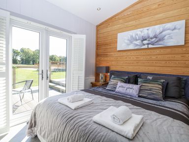 A bedroom with a bed and towels on top at Angel Lodge - No 27 in Fornham St Genevieve near Bury St Edmunds