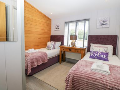 A bedroom with two beds and a wooden table at Angel Lodge - No 27 Fornham St Genevieve near Bury St Edmunds