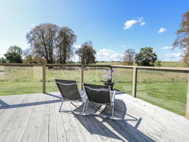An outdoor area with chairs on a deck at Angel Lodge - No 27 in Fornham St Genevieve near Bury St Edmunds