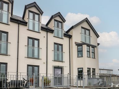 A modern three story building with large windows and balconies at Sandy Bay Retreat in Benllech