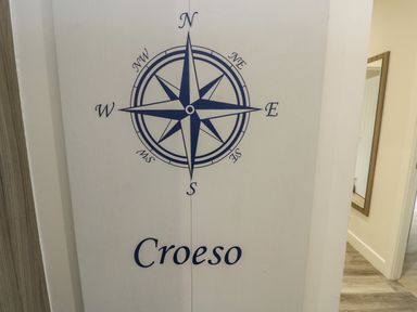 A wall with a compass rose and the word Croeso next to a hallway with a mirror at Sandy Bay Retreat in Benllech