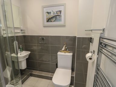 A bathroom with a toilet sink shower and towel rack at Sandy Bay Retreat in Benllech