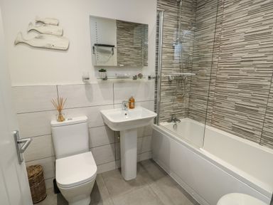 A bathroom with a toilet sink and bathtub with a shower at Sandy Bay Retreat in Benllech