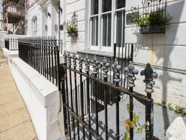 Black metal railing in front of white building with flower boxes on windows at Flat 1 - Sandbanks in Bournemouth