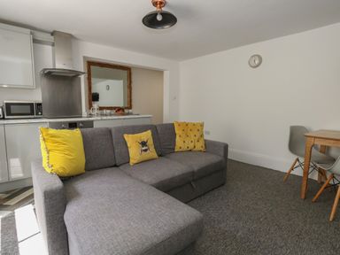 A living room with a gray sofa with yellow pillows and a small dining table with two chairs at Flat 1 - Sandbanks in Bournemouth
