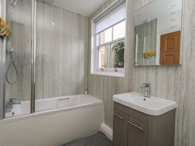 A bathroom with a bathtub shower combination sink cabinet mirror and window at Flat 1 - Sandbanks in Bournemouth