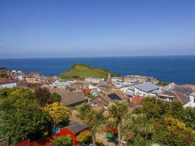 A coastal town with houses and greenery overlooking a hill and the sea at Combe View in Ilfracombe