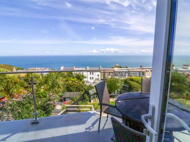 A balcony with a table and chairs overlooking the sea at Combe View, Ilfracombe